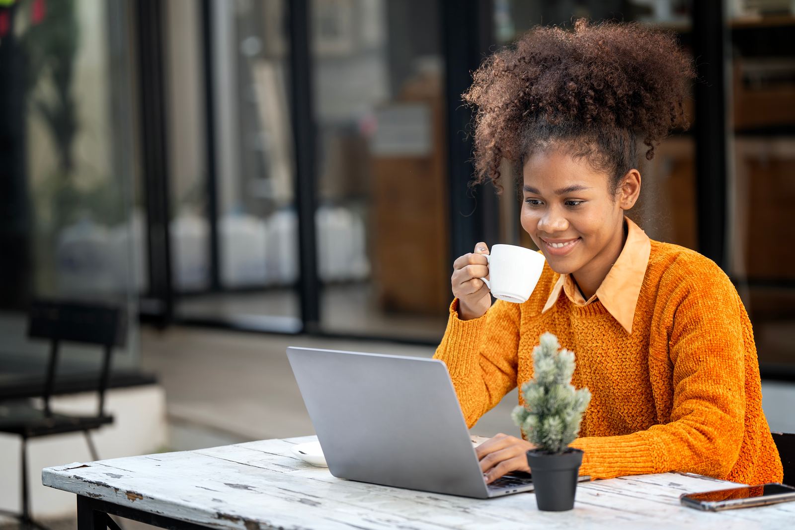 A relaxed business owner enjoying coffee at her laptop — technology handled